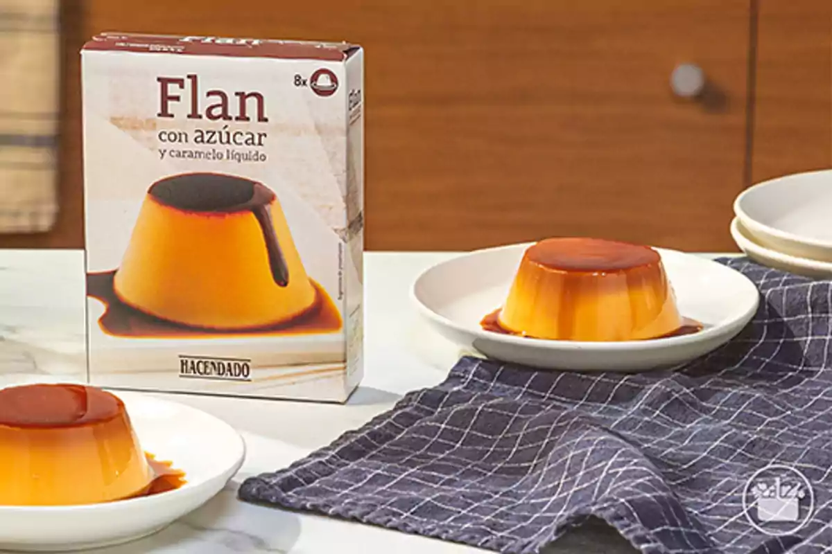 Caixa de flam amb sucre i caramel líquid de la marca Hacendado al costat de dues porcions servides en plats sobre un estovalles blau. Caixa de flam amb sucre i caramel líquid de la marca Hacendado al costat de dues porcions servides en plats sobre un estovalles blau.