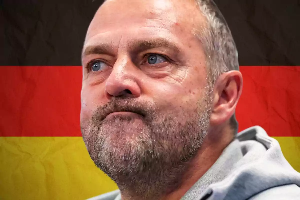 Serious-looking man with a beard and short hair in front of a blurred German flag