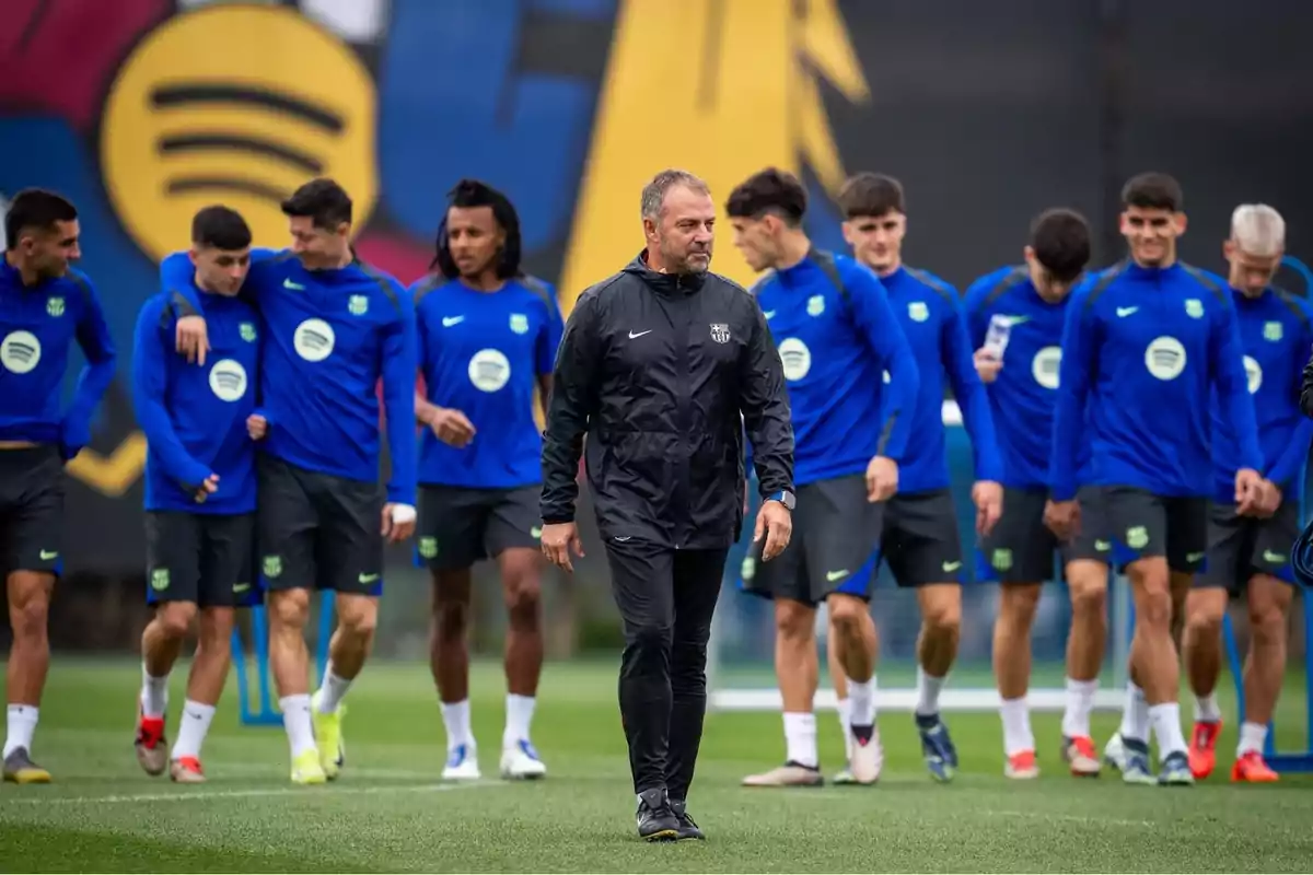 Soccer coach walking in front while Barcelona players train on the field in blue uniforms Soccer coach walking in front while Barcelona players train on the field in blue uniforms