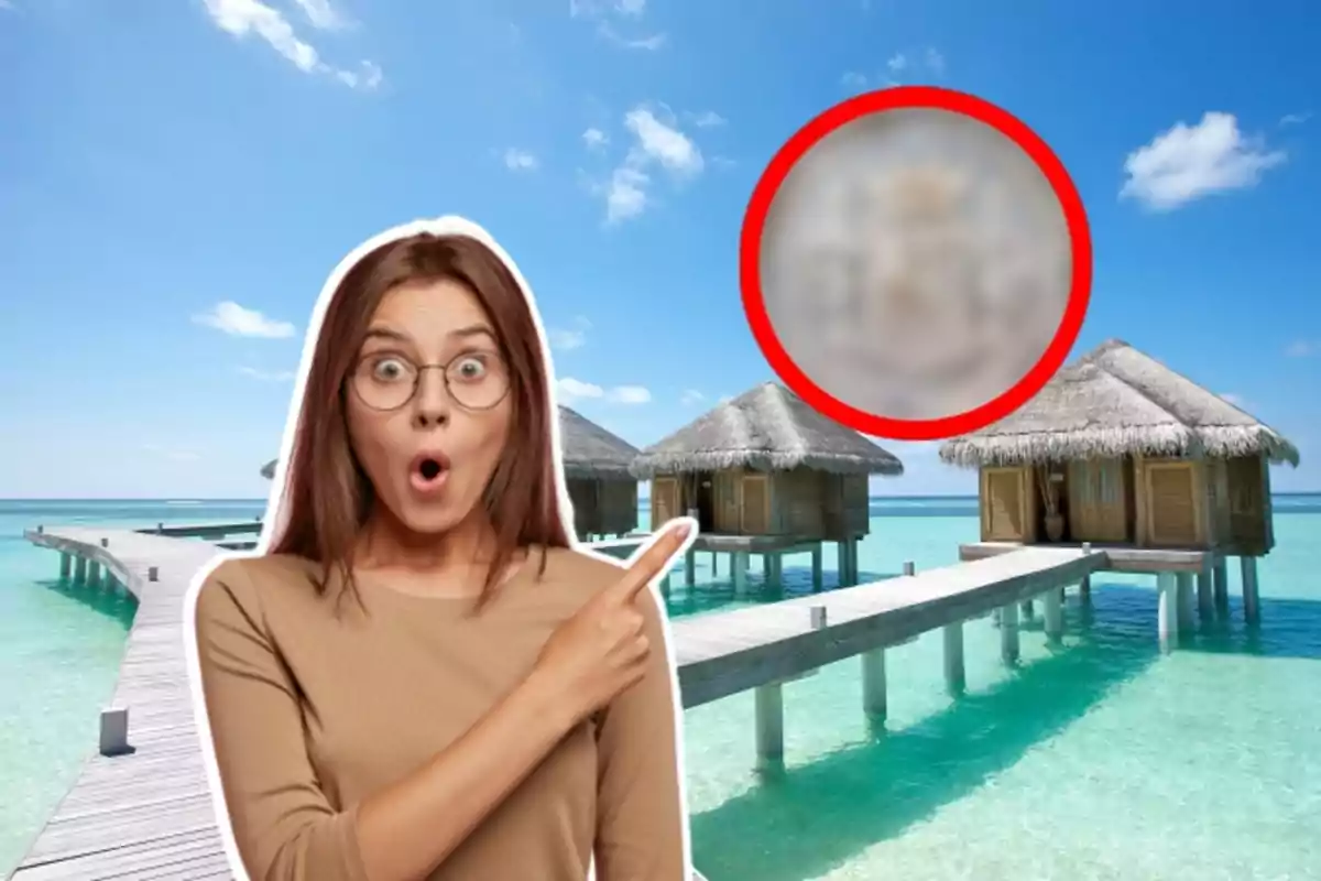 Dona sorpresa assenyalant cap a un grup de bungalous sobre l'aigua en un entorn tropical.