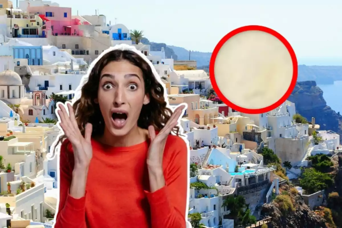 Una dona sorpresa amb les mans al rostre sobre un fons de cases blanques i acolorides en un turó al costat del mar, amb un cercle vermell ressaltant una àrea borrosa.