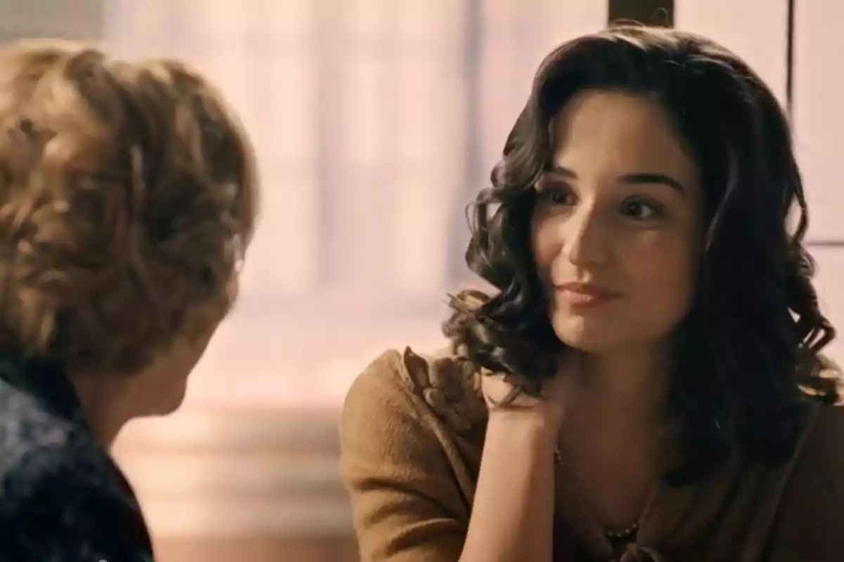 Cristina (Sara Sanz) i una altra dona conversen en un ambient interior il·luminat, una d’elles somriu lleument mentre escolta l’altra. Cristina (Sara Sanz) i una altra dona conversen en un ambient interior il·luminat, una d’elles somriu lleument mentre escolta l’altra.
