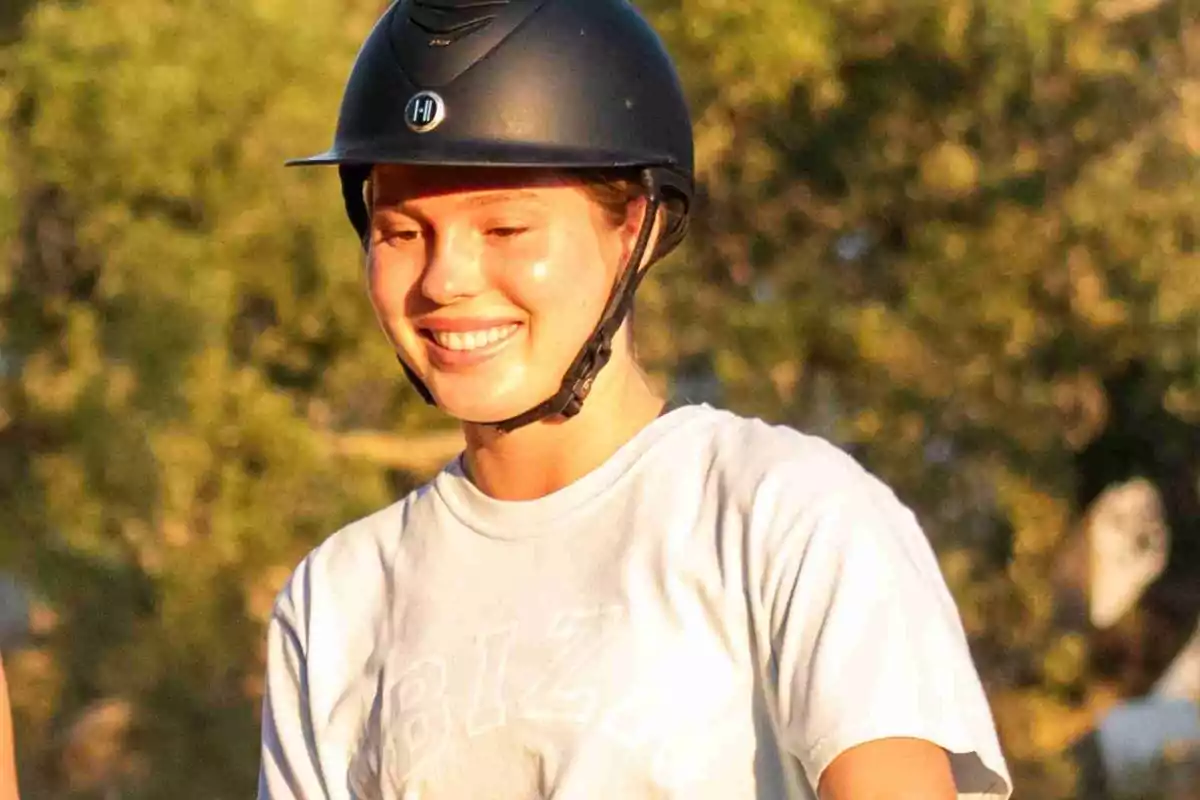 Cristina Iglesias smiling with a riding helmet in an outdoor setting. Cristina Iglesias smiling with a riding helmet in an outdoor setting.