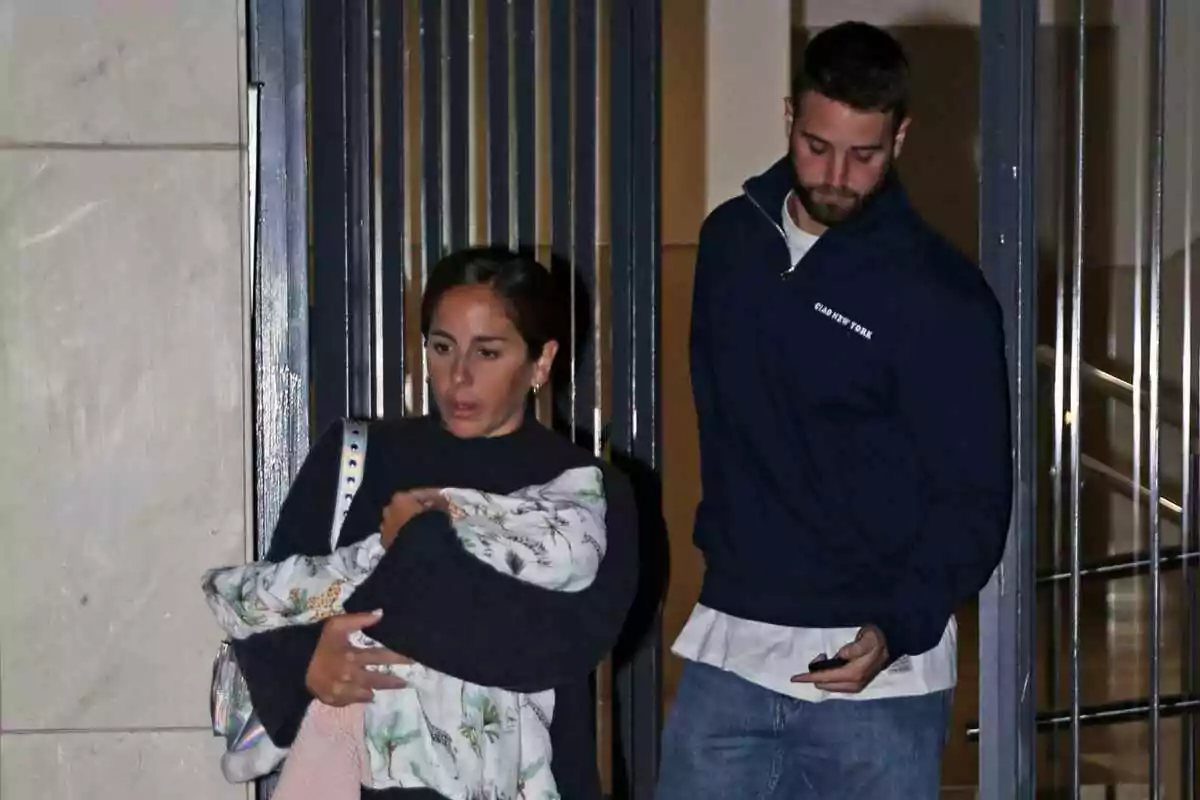 Anabel Pantoja i David Rodríguez surten d'un edifici, Anabel porta un nadó embolicat en una manta.