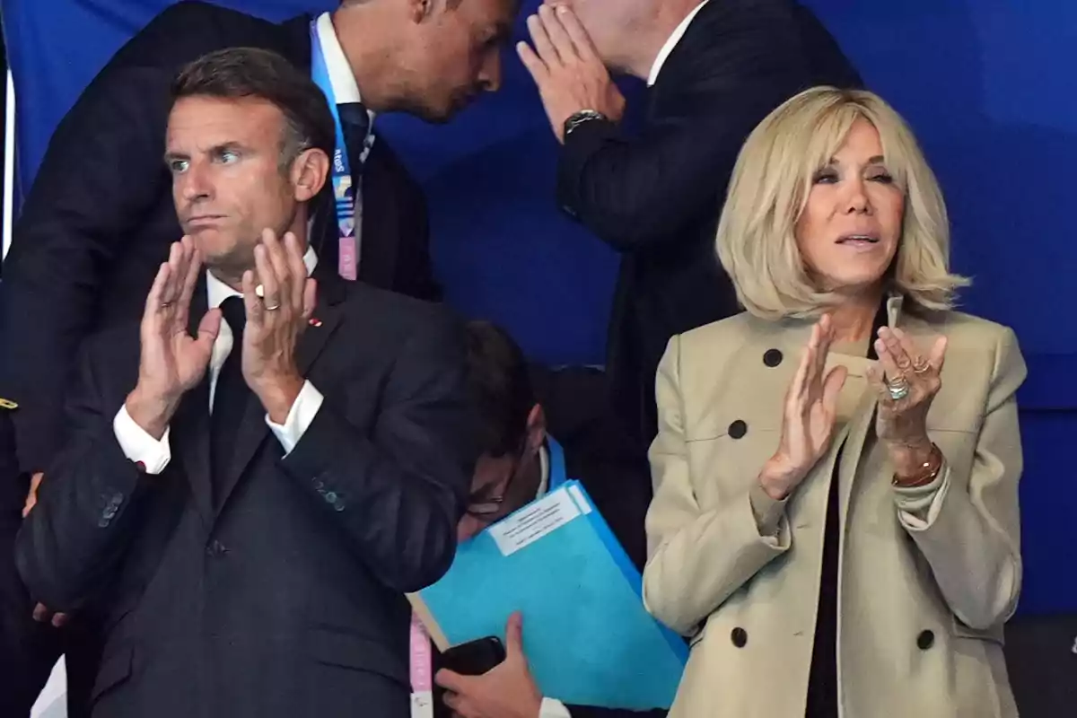 Emmanuel Macron y Brigitte Macron aplauden en un evento mientras otras personas conversan detrás de ellos Emmanuel Macron y Brigitte Macron aplauden en un evento mientras otras personas conversan detrás de ellos
