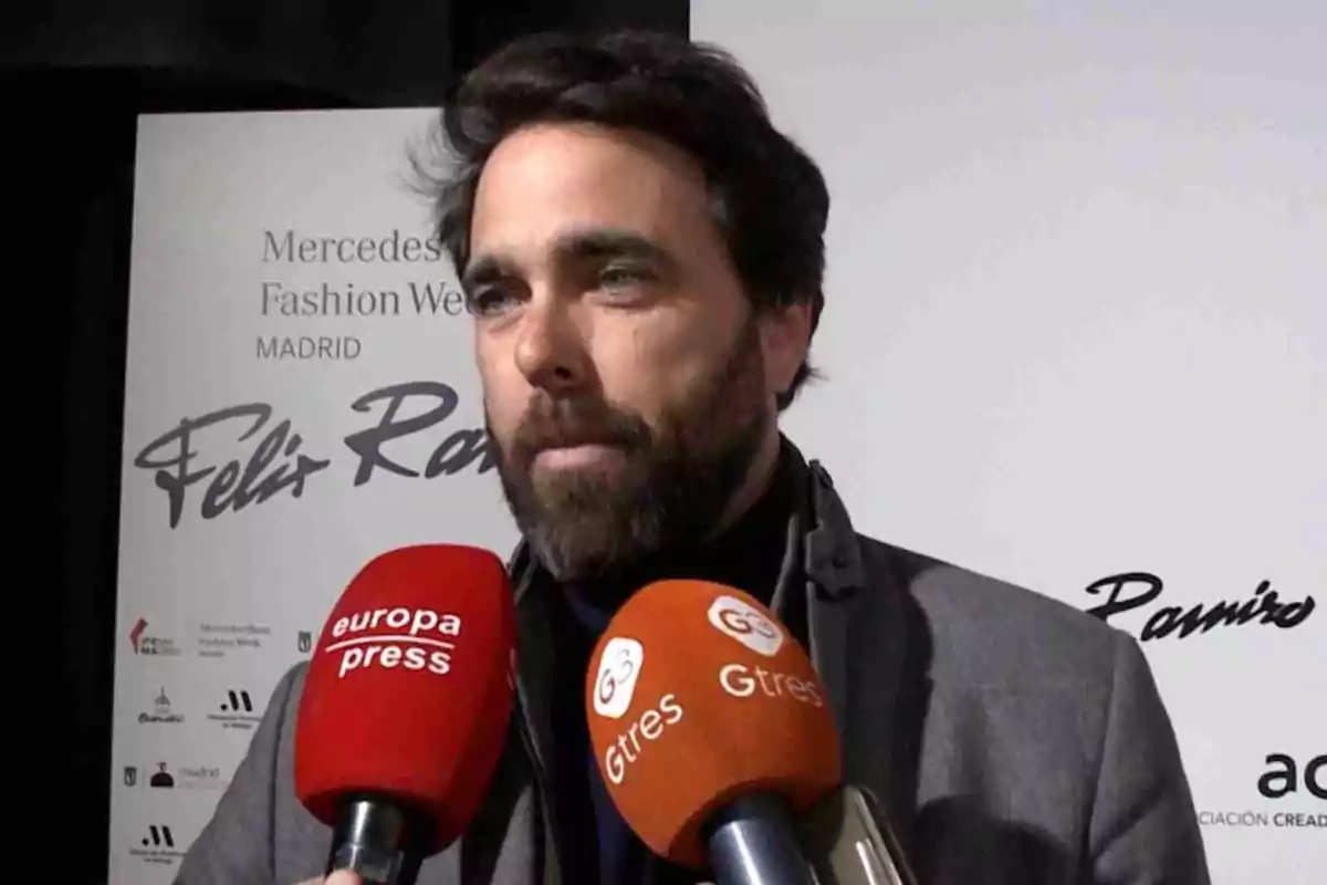 Javier Ungría amb barba i cabell fosc està parlant davant de diversos micròfons de premsa en un esdeveniment de moda a Madrid. Javier Ungría amb barba i cabell fosc està parlant davant de diversos micròfons de premsa en un esdeveniment de moda a Madrid.