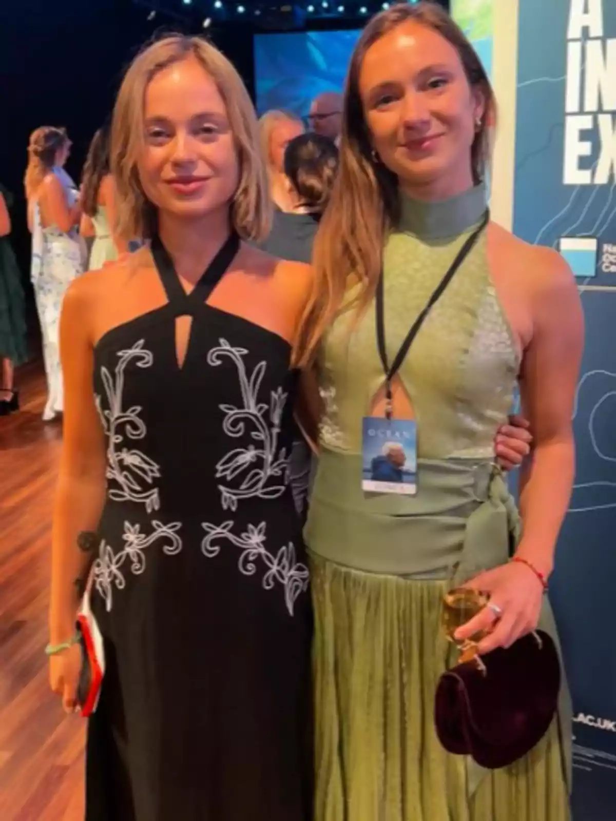 Marina Windsor posen somrients amb una dona en un esdeveniment elegant, ella porta un vestit negre amb detalls blancs i Marina un vestit verd clar, ambdues estan abraçades i envoltades d’altres persones en un ambient il·luminat. Marina Windsor posen somrients amb una dona en un esdeveniment elegant, ella porta un vestit negre amb detalls blancs i Marina un vestit verd clar, ambdues estan abraçades i envoltades d’altres persones en un ambient il·luminat.