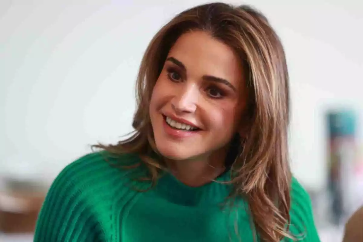Rania of Jordan smiling in a green sweater. Rania of Jordan smiling in a green sweater.