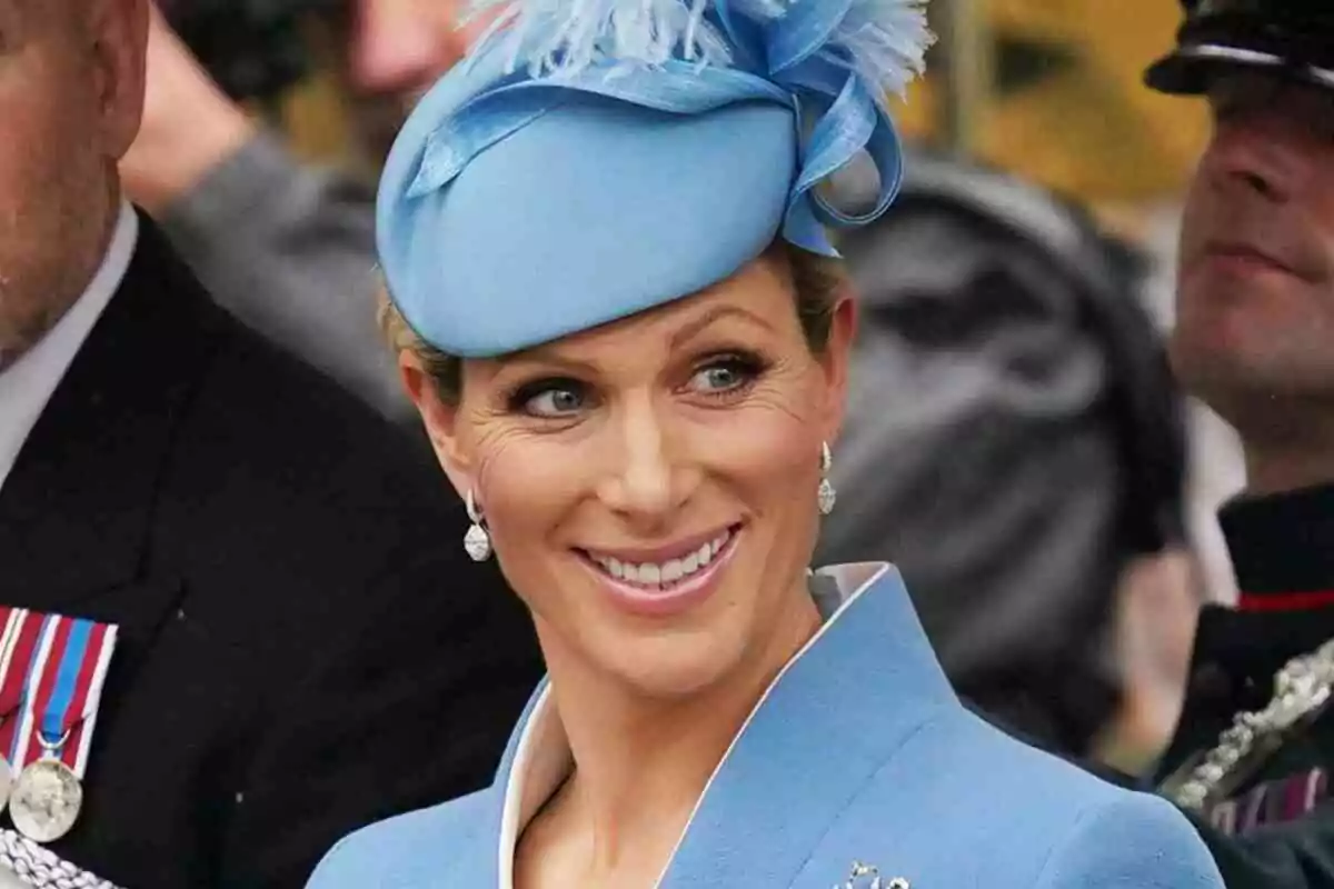 Zara Tindall somrient amb un barret blau clar adornat amb plomes. Zara Tindall somrient amb un barret blau clar adornat amb plomes.