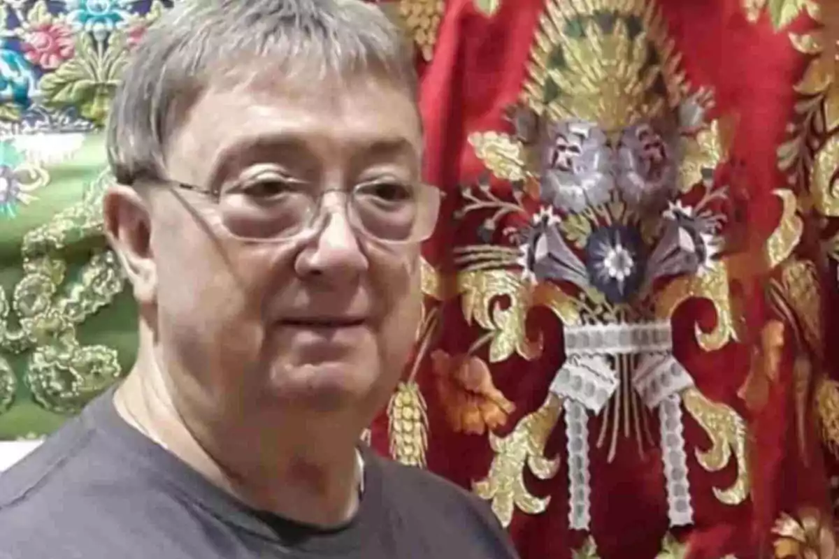 Enrique Marzal con cabello canoso y gafas frente a telas coloridas con bordados detallados