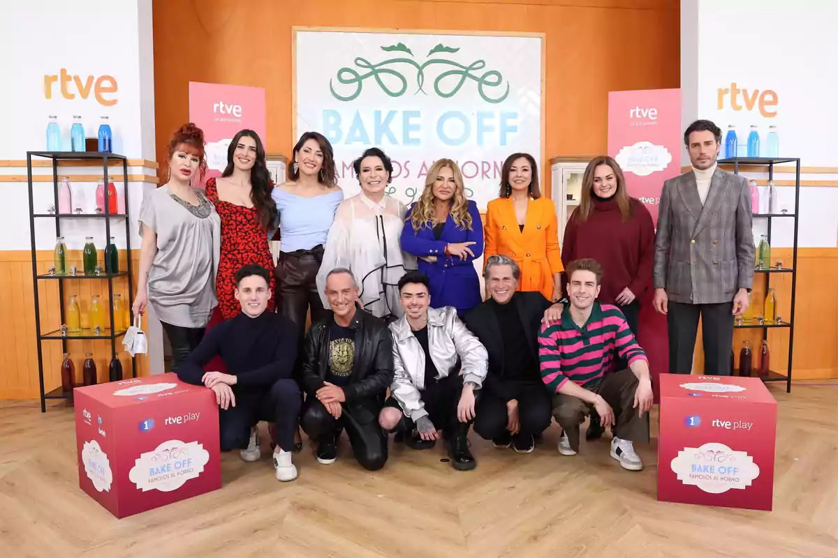 Un grupo de personas posando en un set de televisión con el logo de 