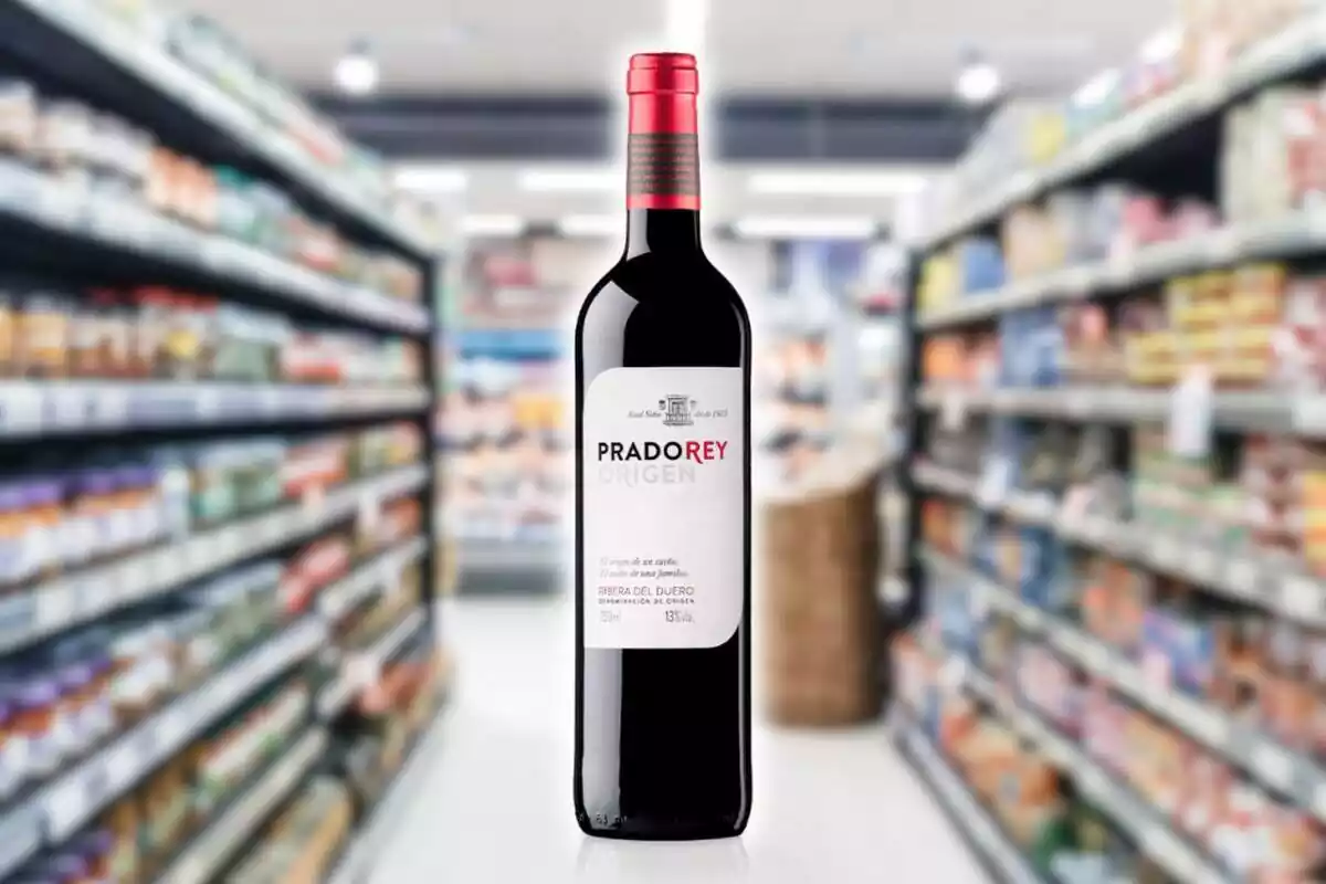 Fotomontaje de una botella de vino Prado Rey Origen 2021 al frente y de fondo una imagen de las estanterías de un supermercado difuminadas