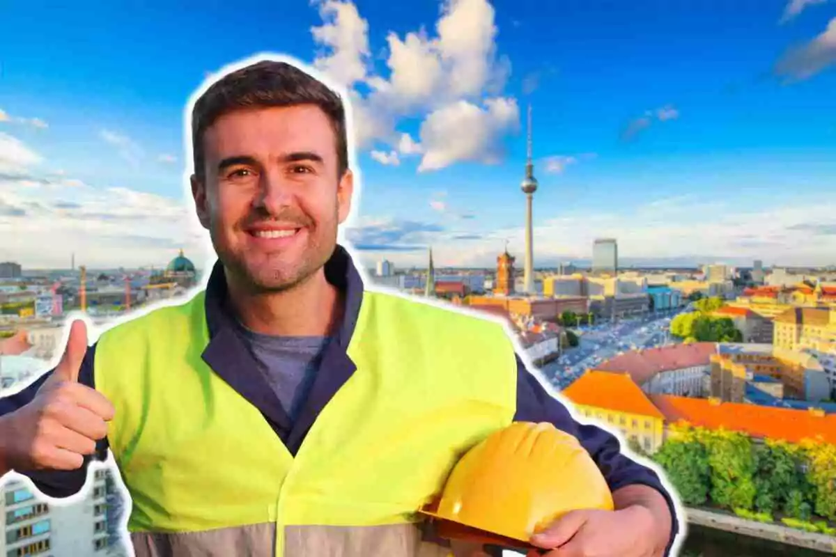 Home amb armilla de seguretat i casc groc a la mà, somrient i mostrant el polze cap amunt amb una ciutat de fons.
