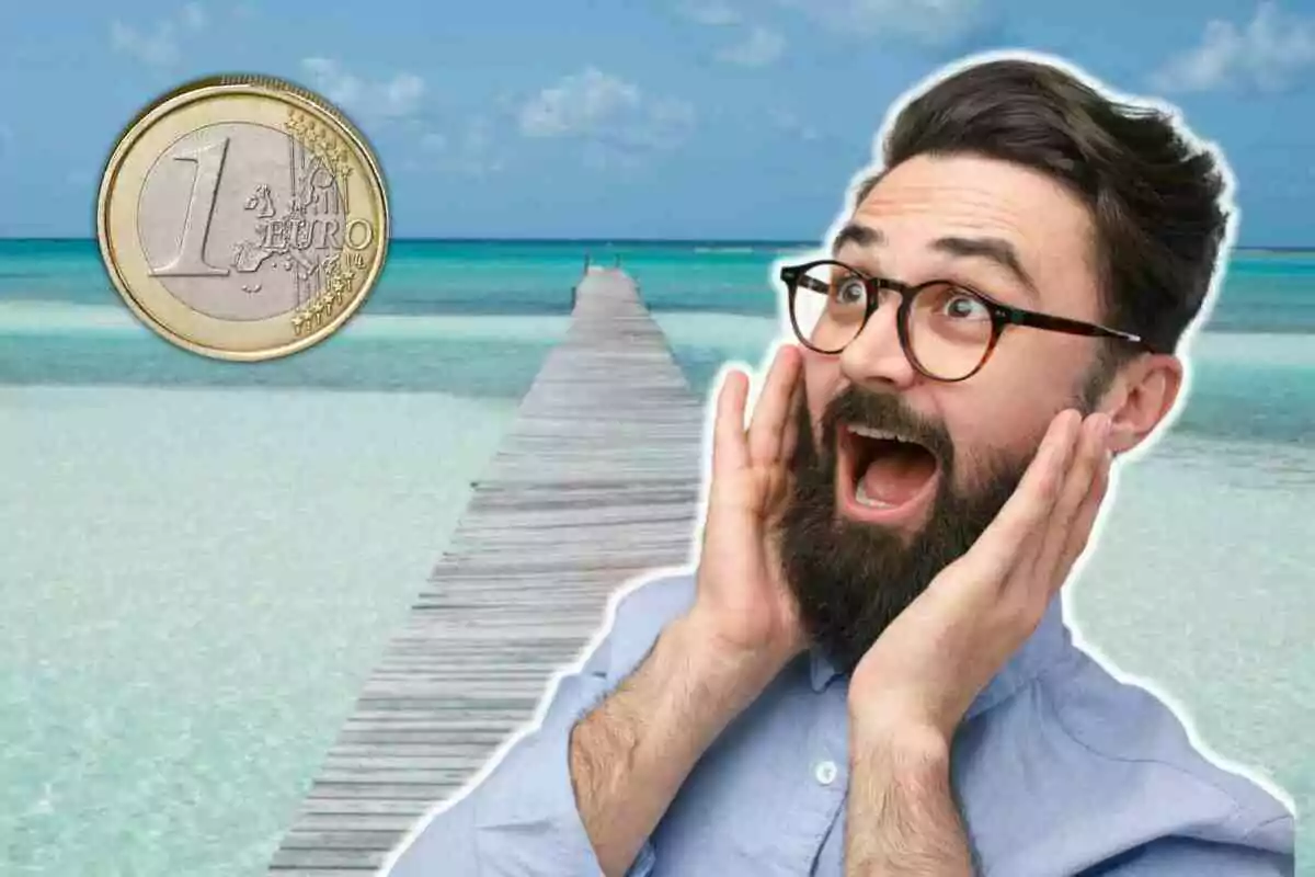 Un home amb expressió de sorpresa al costat d?una moneda d?un euro sobre un fons de platja amb un moll.