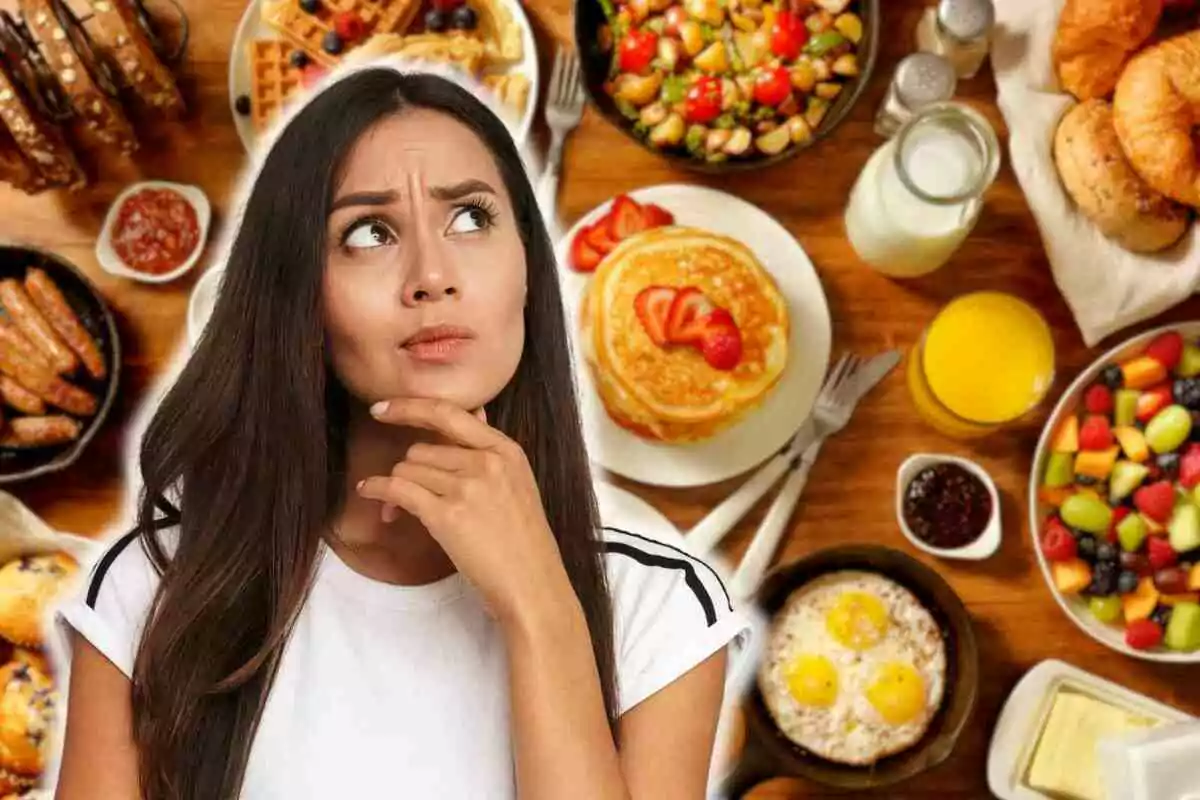 Dona pensativa davant d'una taula plena d'opcions d'esmorzar com pancakes, fruites, ous i suc.