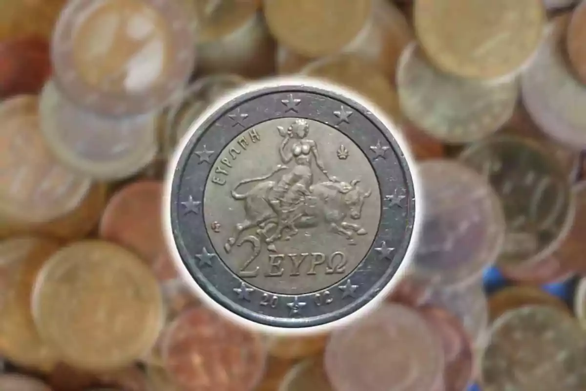 Moneda de dos euros amb disseny de dona muntant un bou sobre un fons d'altres monedes desenfocades. Moneda de dos euros amb disseny de dona muntant un bou sobre un fons d'altres monedes desenfocades.