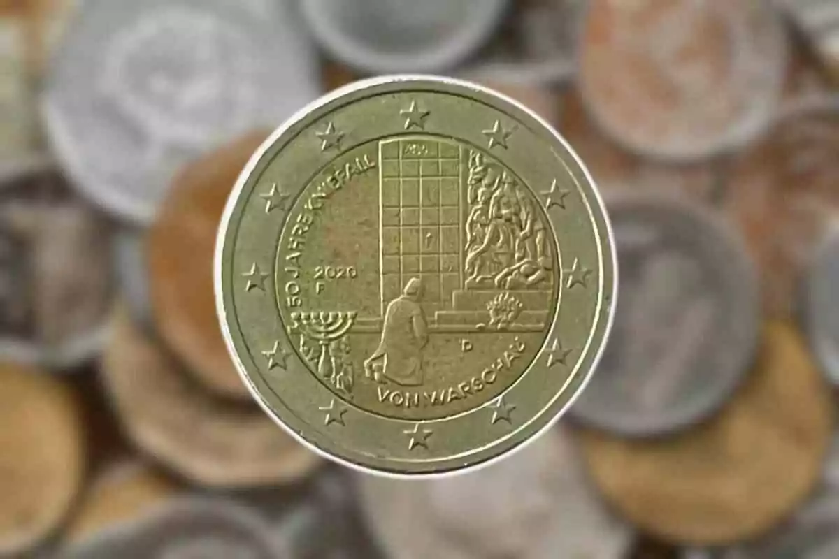 Moneda commemorativa de dos euros amb disseny que inclou una figura humana davant d'un monument i un canelobre, envoltada d'estrelles sobre un fons d'altres monedes desenfocades. Moneda commemorativa de dos euros amb disseny que inclou una figura humana davant d'un monument i un canelobre, envoltada d'estrelles sobre un fons d'altres monedes desenfocades.