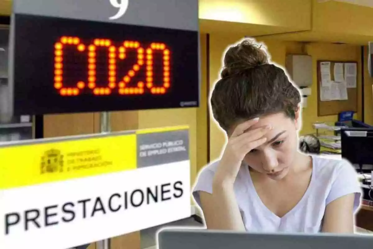 Una dona amb expressió preocupada en una oficina de prestacions, amb un rètol electrònic que mostra el número C020 i un cartell del Ministeri de Treball i Migracions.