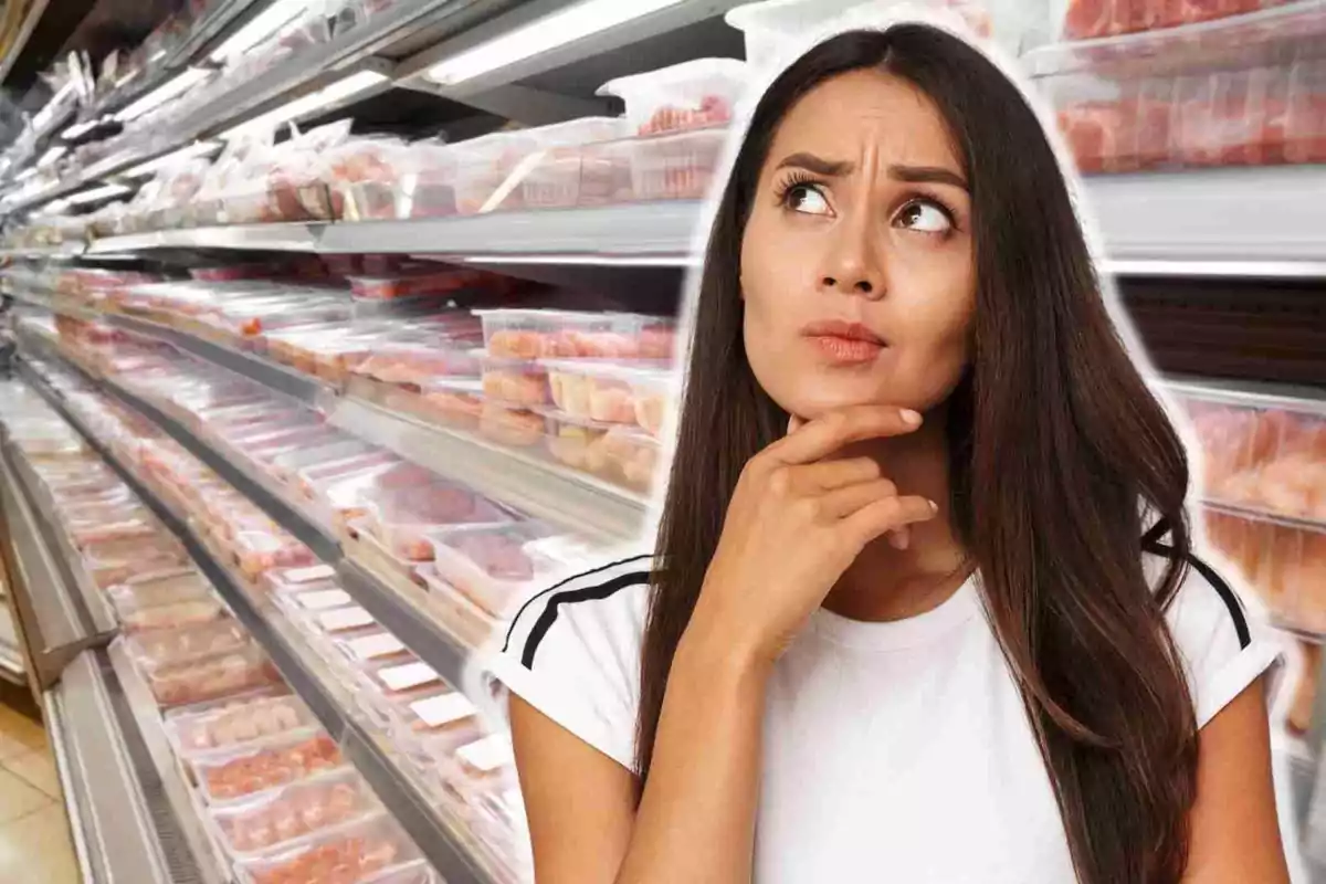 Dona pensativa en un passadís de supermercat ple de productes envasats.