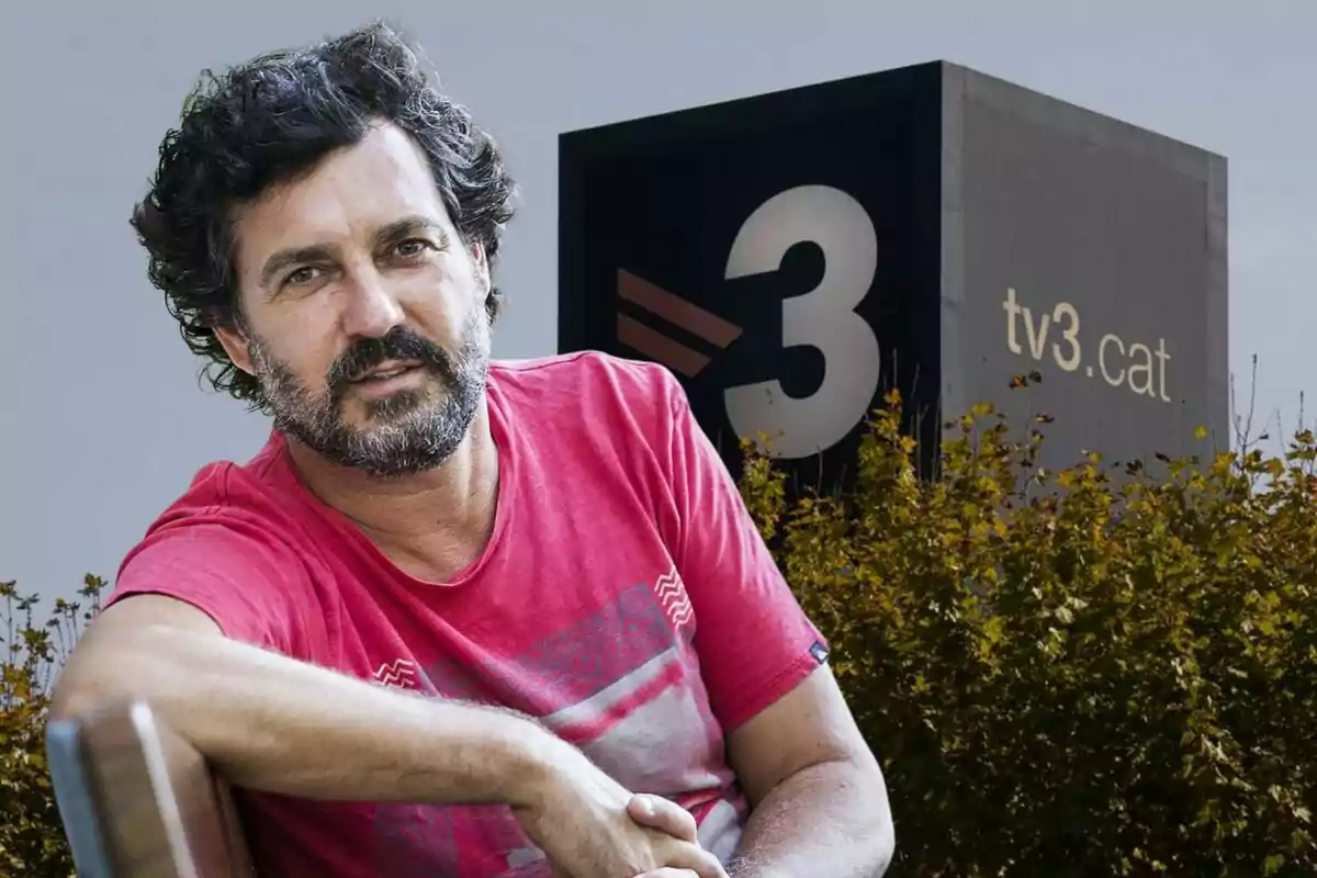 Un home amb barba i cabell arrissat, vestit amb una samarreta vermella, està assegut davant d'un edifici amb el logotip de “tv3.cat”.