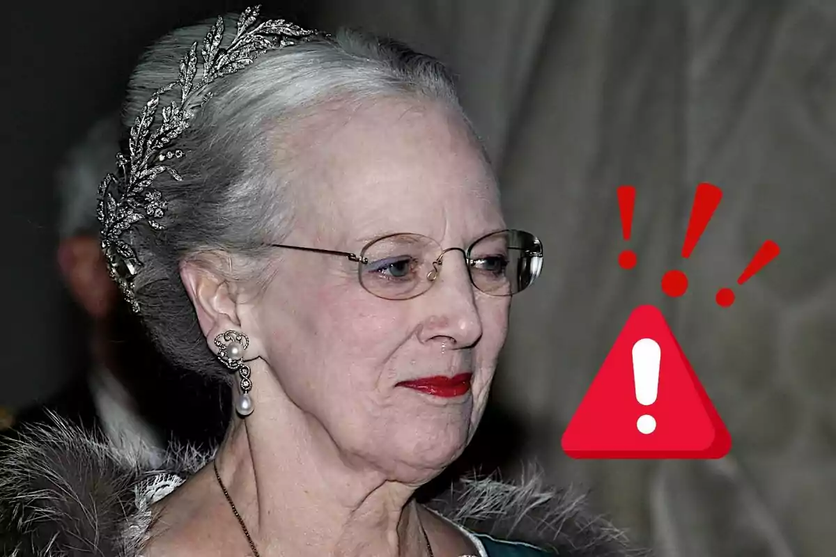 Una persona gran amb ulleres i una tiara, al costat d'una icona d'advertència en vermell.