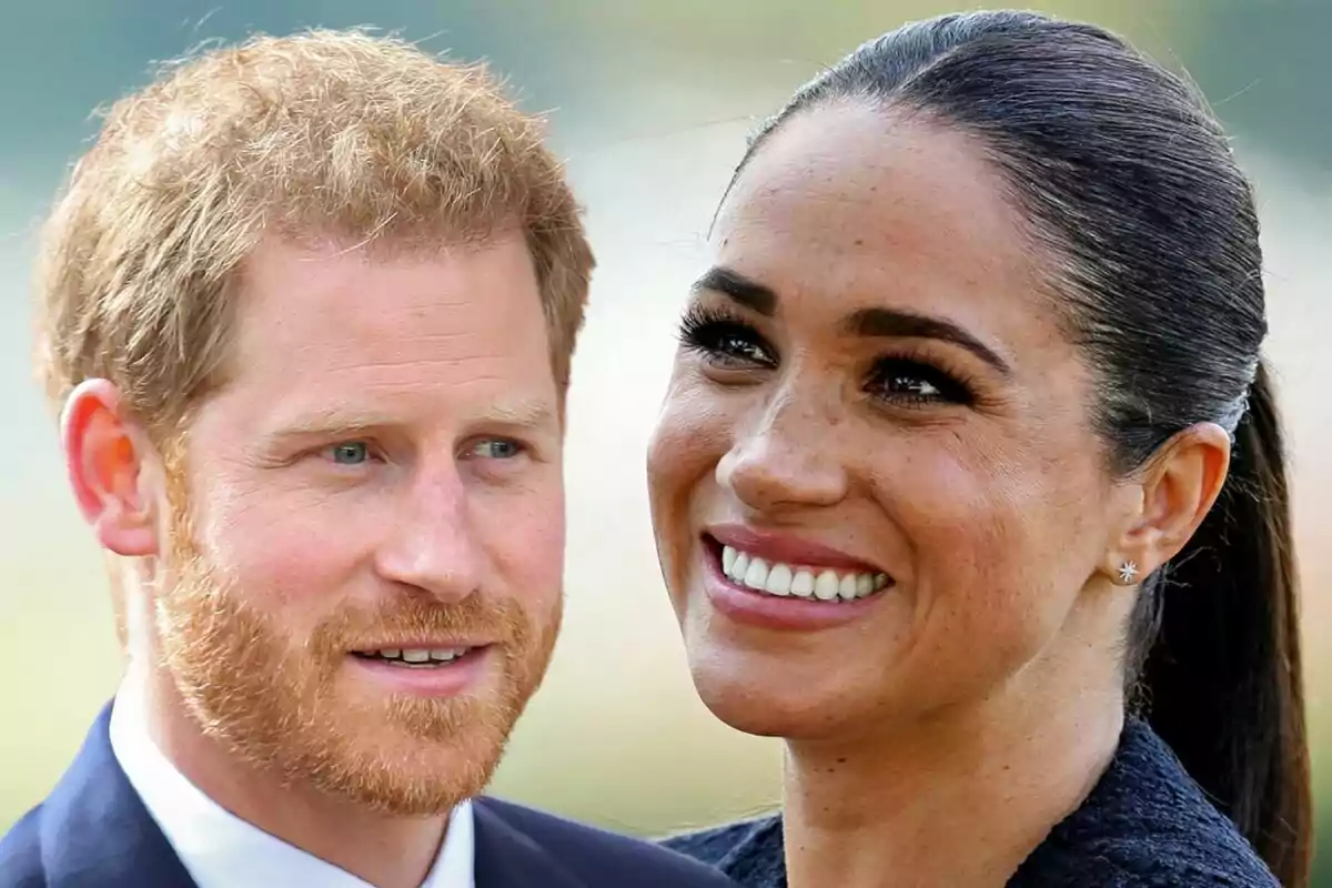 A red-haired bearded man and a woman with dark hair tied back smile together outdoors.