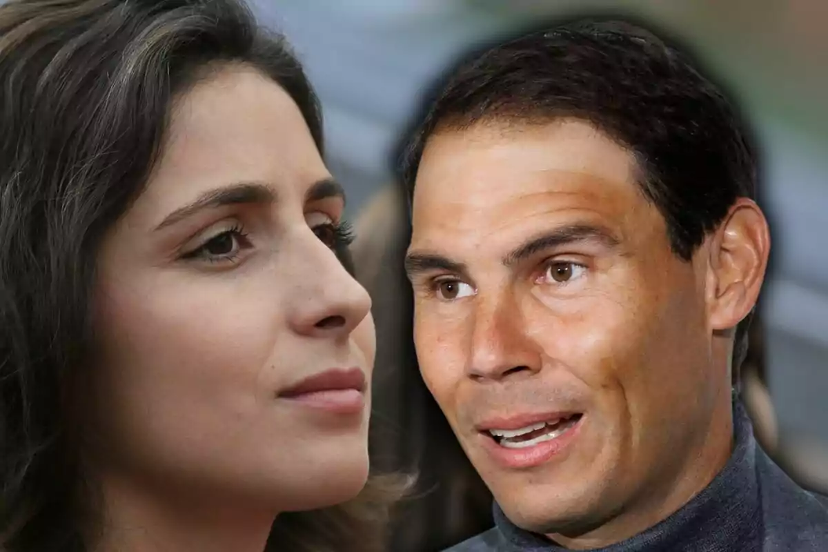 Close-up of a dark-haired woman looking to the right and a short dark-haired man with a smiling expression looking to the left, both against a blurred background.