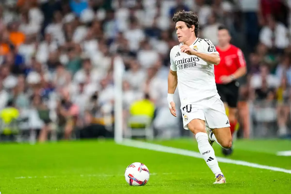 Un jugador de fútbol con el uniforme blanco del Real Madrid corre con el balón en un estadio lleno de espectadores. Un jugador de fútbol con el uniforme blanco del Real Madrid corre con el balón en un estadio lleno de espectadores.