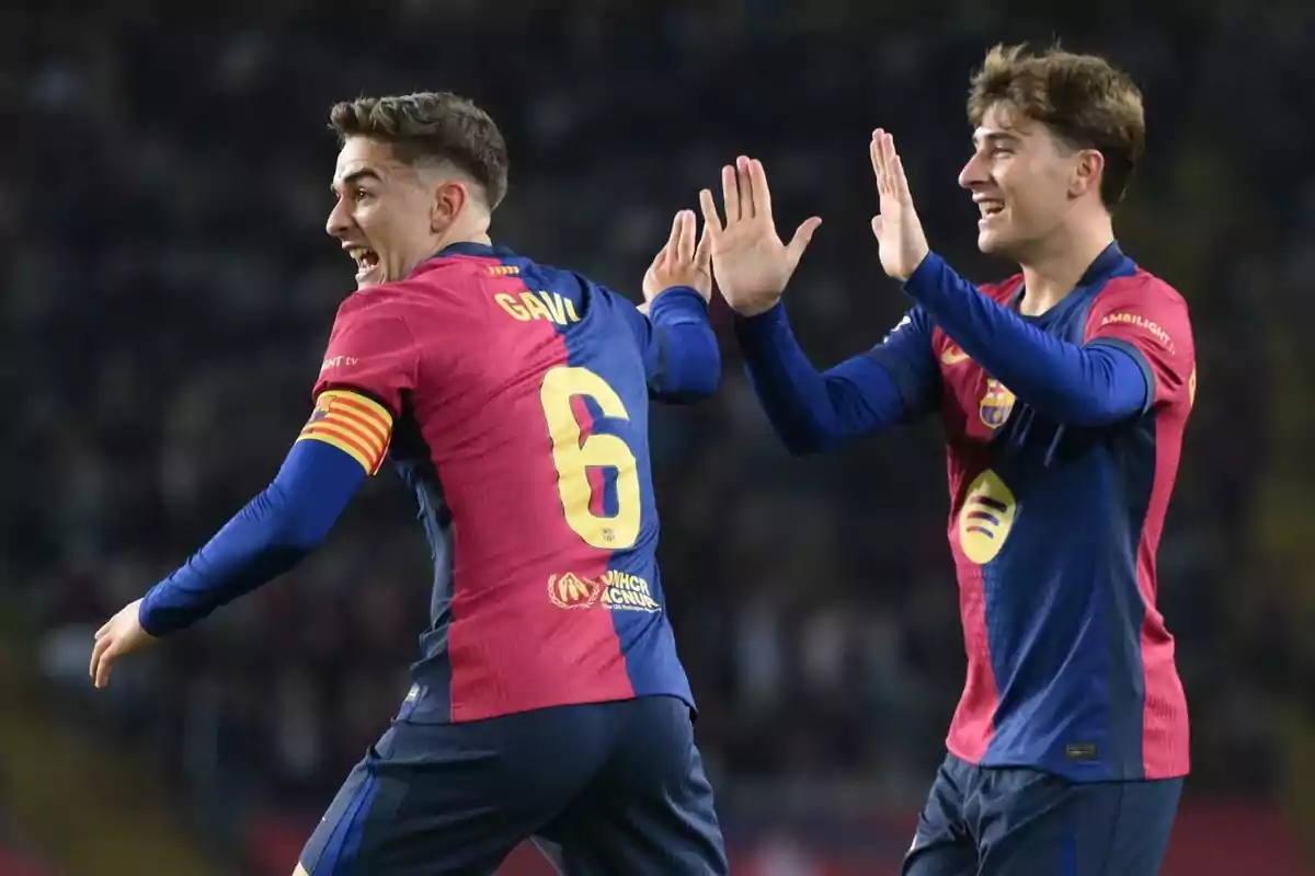Dos jugadors de futbol celebren al camp amb uniformes blau i vermell. Dos jugadors de futbol celebren al camp amb uniformes blau i vermell.