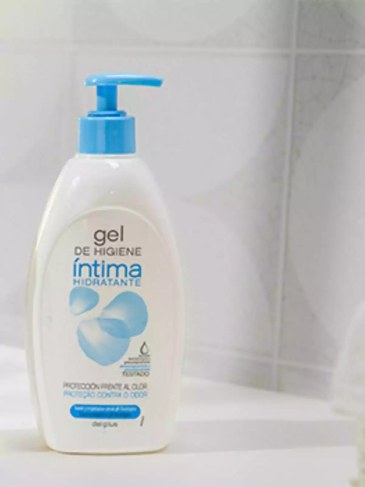 Ampolla de gel d'higiene íntima hidratant amb dispensador blau sobre una superfície blanca. Ampolla de gel d'higiene íntima hidratant amb dispensador blau sobre una superfície blanca.