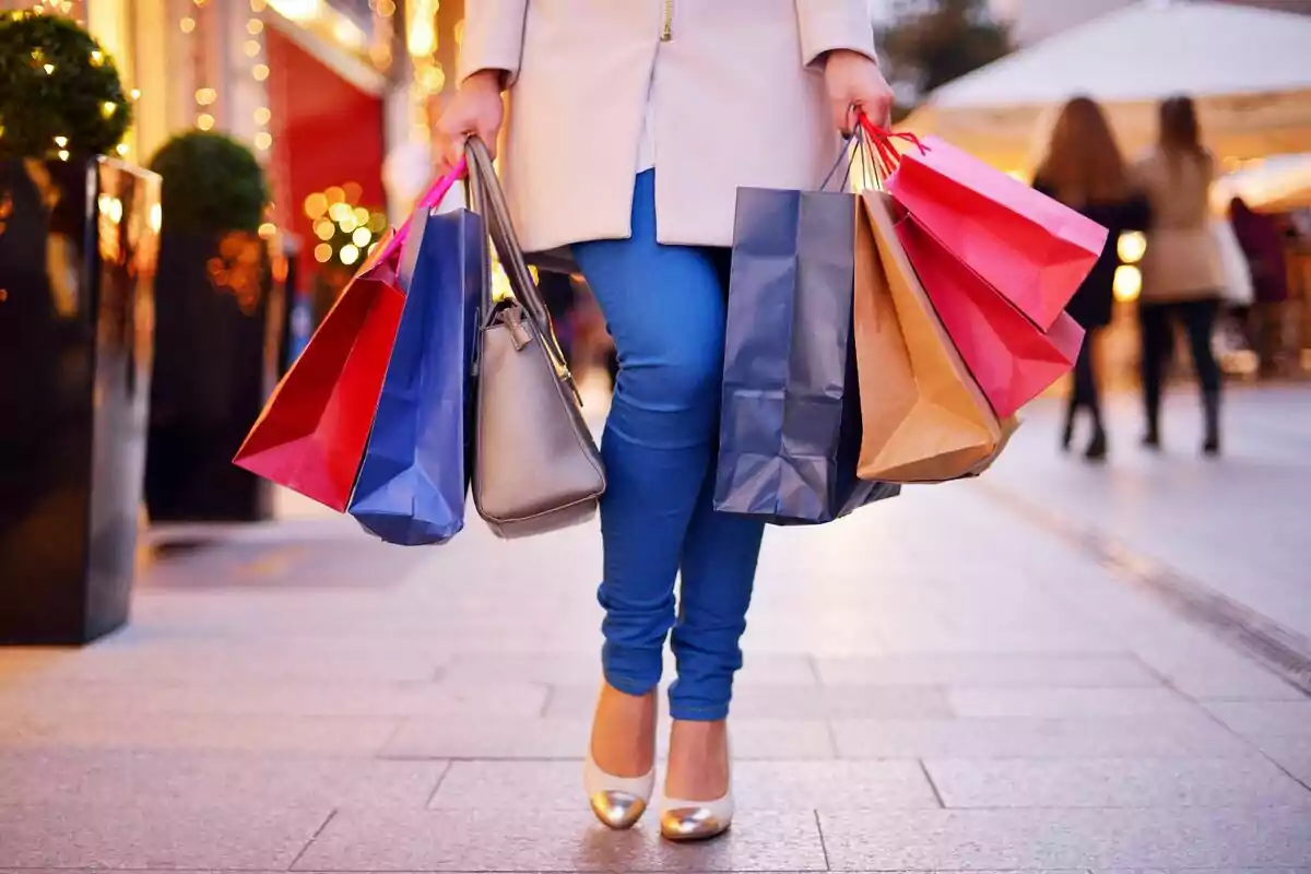 Persona caminant pel carrer amb diverses bosses de compra a les mans durant un dia de compres