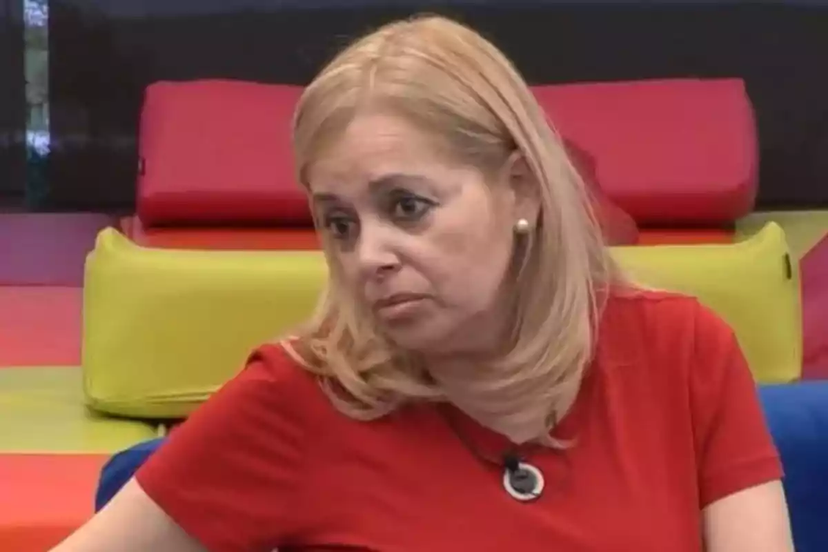 Emma Ozores amb expressió seriosa porta una samarreta vermella i està asseguda davant d'un fons de coixins de colors brillants. Emma Ozores amb expressió seriosa porta una samarreta vermella i està asseguda davant d'un fons de coixins de colors brillants.