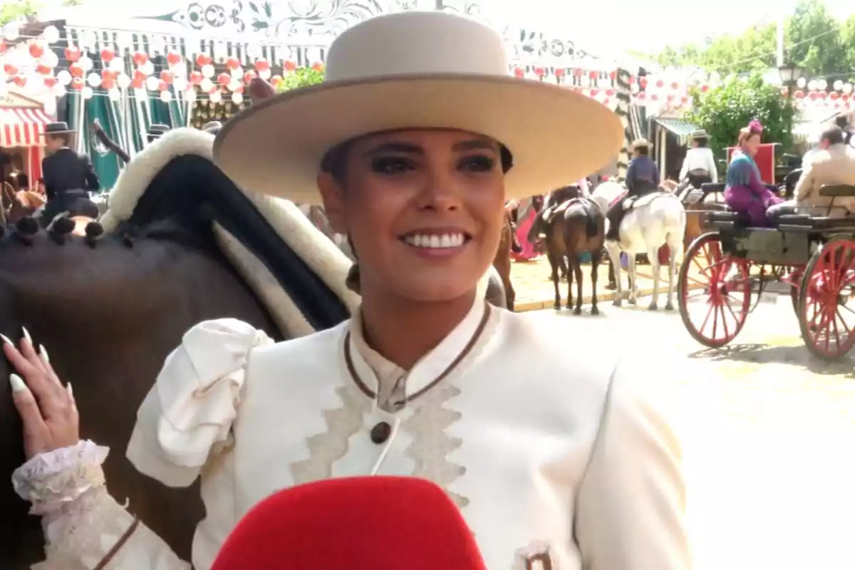 Gloria Camila somrient amb barret i vestit tradicional posa al costat d'un cavall en un esdeveniment a l'aire lliure amb carretes i persones vestides d'època. Gloria Camila somrient amb barret i vestit tradicional posa al costat d'un cavall en un esdeveniment a l'aire lliure amb carretes i persones vestides d'època.