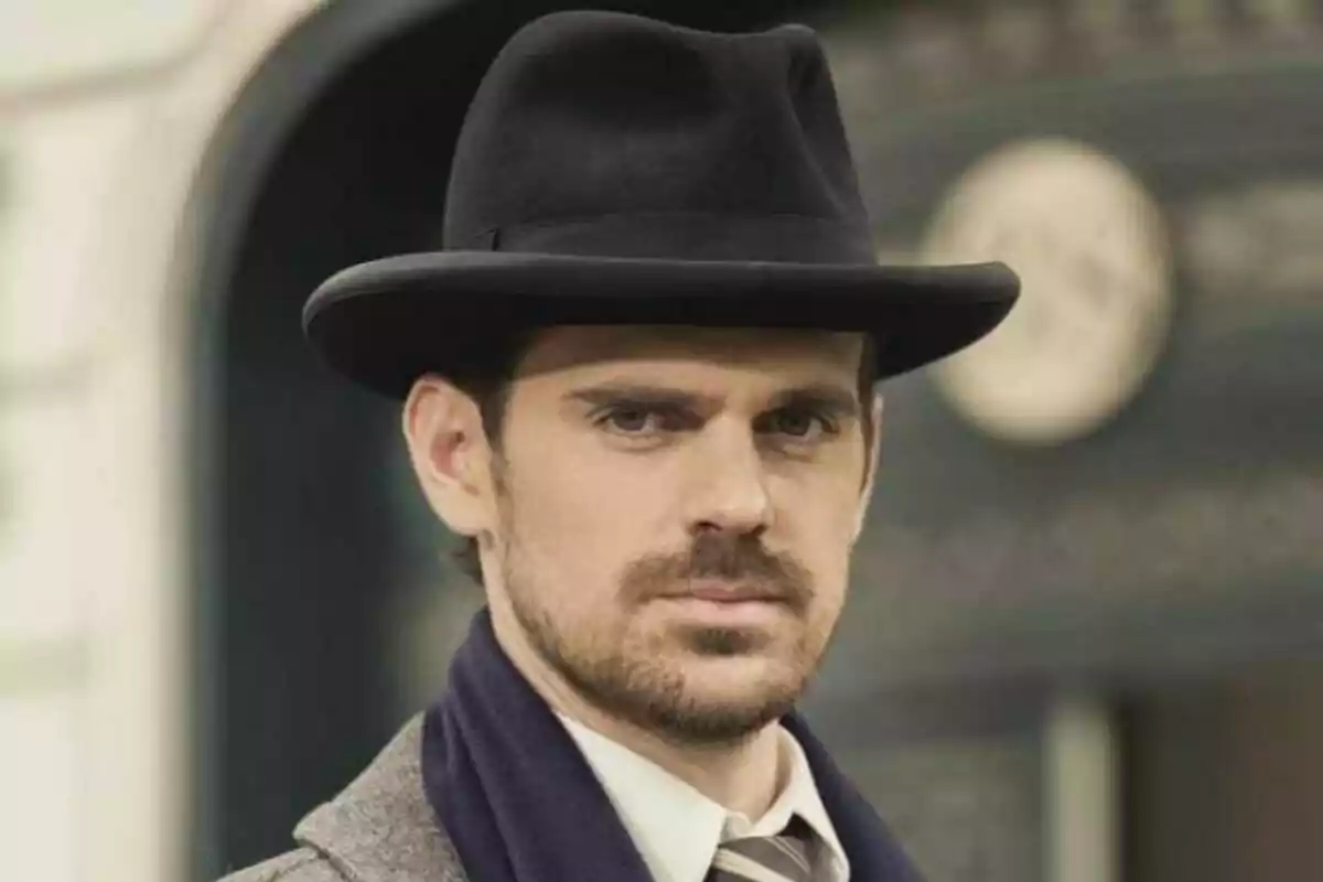 Gonzalo Ramos amb barret negre i barba, vestint un abric i corbata, mira cap a la càmera amb expressió seriosa. Gonzalo Ramos amb barret negre i barba, vestint un abric i corbata, mira cap a la càmera amb expressió seriosa.