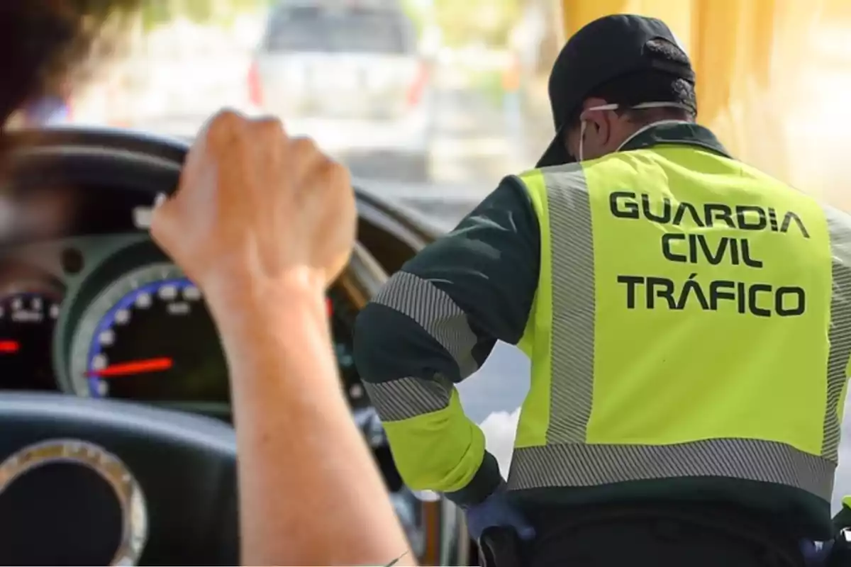 Un agent de la Guàrdia Civil de Trànsit amb armilla reflectora interactua amb un conductor en un control de carretera.