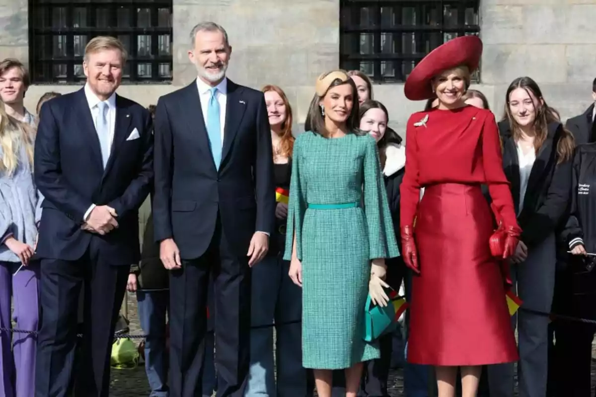 Guillem d'Holanda, Felip VI, Letizia i Màxima d'holanda posant per a una foto, tots vestits de manera elegant, mentre que diverses persones al fons observen i somriuen. Guillem d'Holanda, Felip VI, Letizia i Màxima d'holanda posant per a una foto, tots vestits de manera elegant, mentre que diverses persones al fons observen i somriuen.