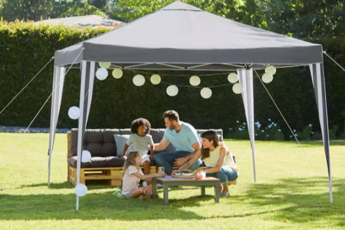 Una família gaudeix d'un pícnic sota una carpa en un jardí, amb llums decoratives penjades. Una família gaudeix d'un pícnic sota una carpa en un jardí, amb llums decoratives penjades.