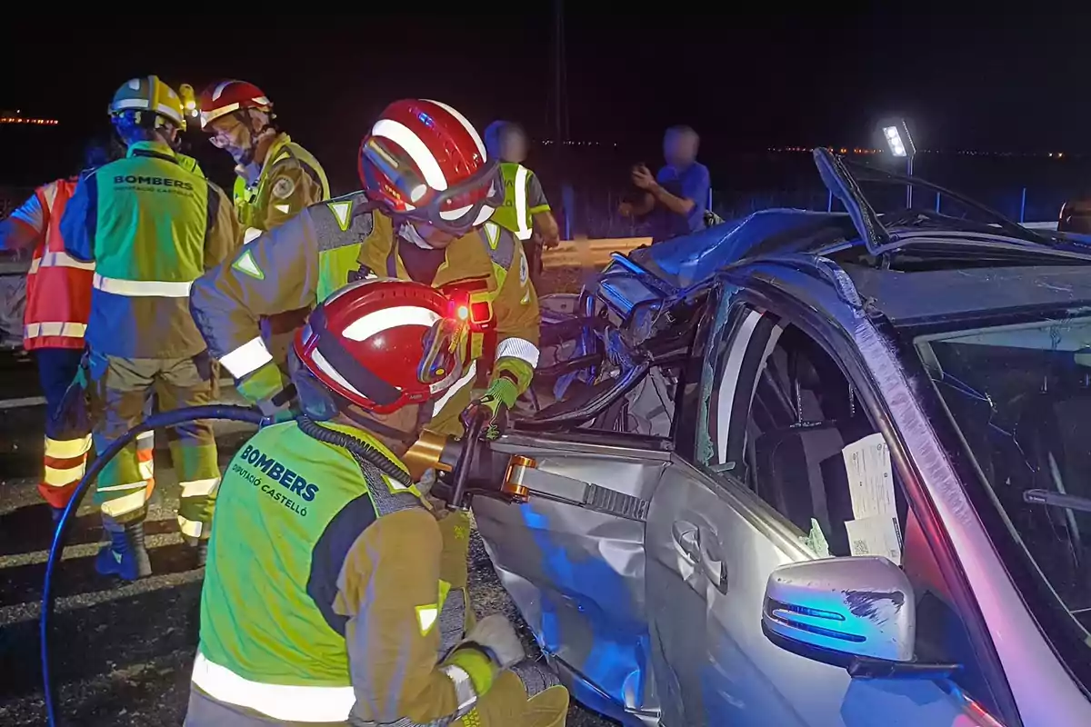 Bombers treballant a l'escena d'un accident automobilístic a la nit.