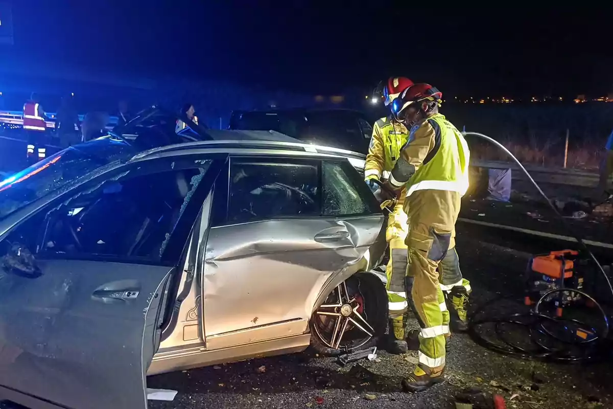 Bombers treballant a l'escena d'un accident automobilístic durant la nit.