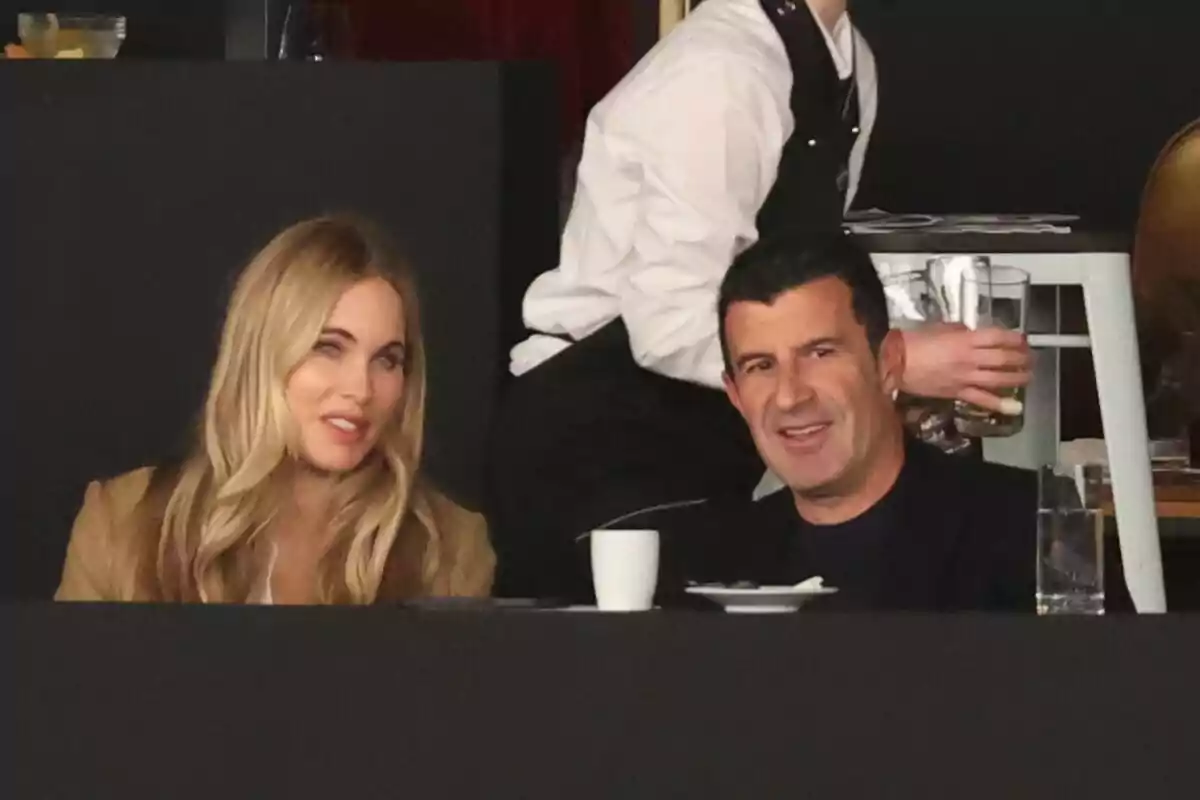 Helen Svedin i Luís Figo assegudes en un restaurant amb un cambrer al fons. Helen Svedin i Luís Figo assegudes en un restaurant amb un cambrer al fons.