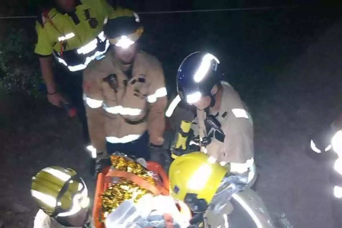 Imatge dels Bombers de la Generalitat amb una llitera acudint al rescat d'un noi que havia caigut amb el cotxe per un precipici al Pallars Jussà, a Sort