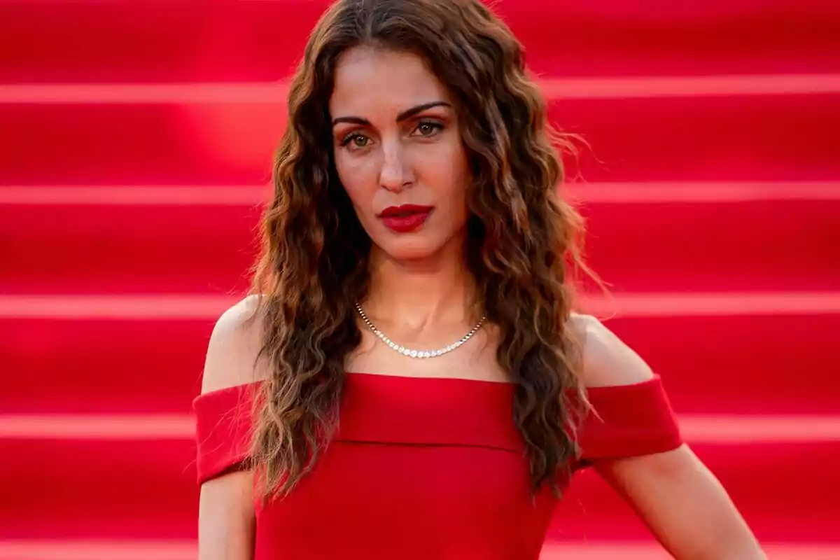 Hiba Abouk amb vestit vermell posant davant una catifa vermella. Hiba Abouk amb vestit vermell posant davant una catifa vermella.