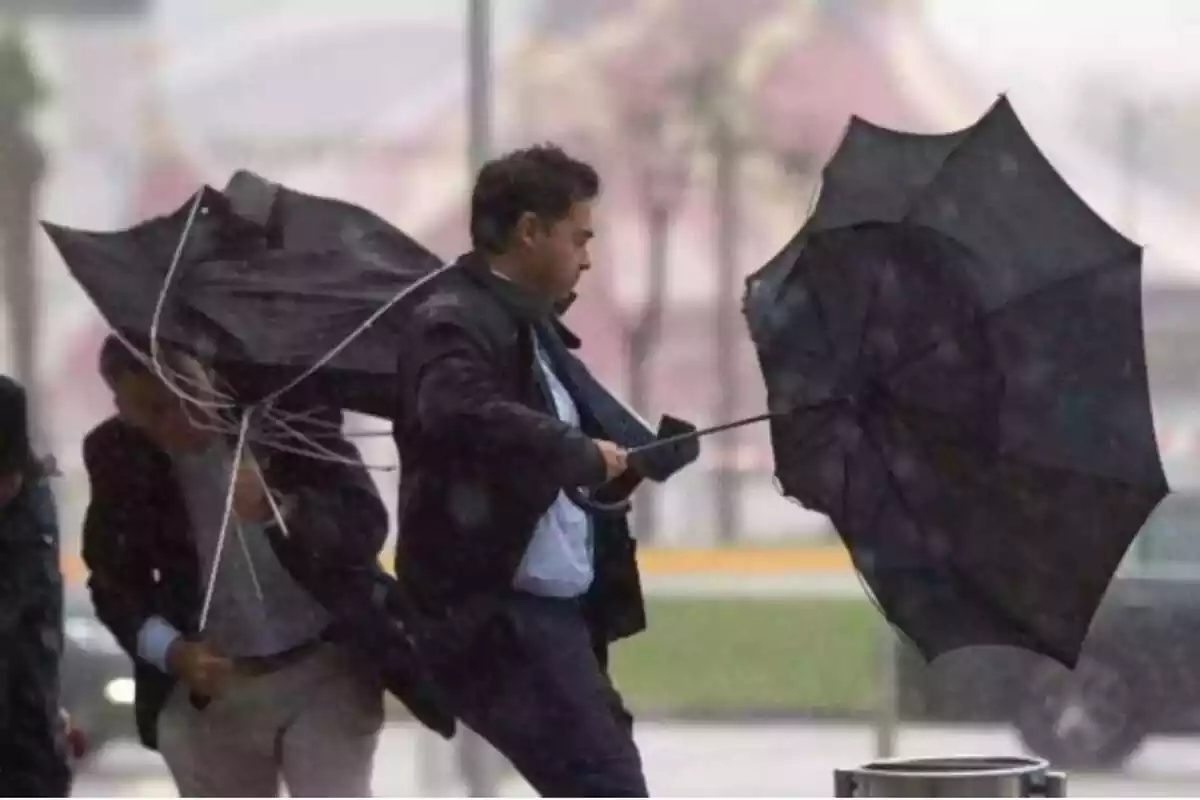 Home amb el paraigua del revés pel temporal de pluja i vent