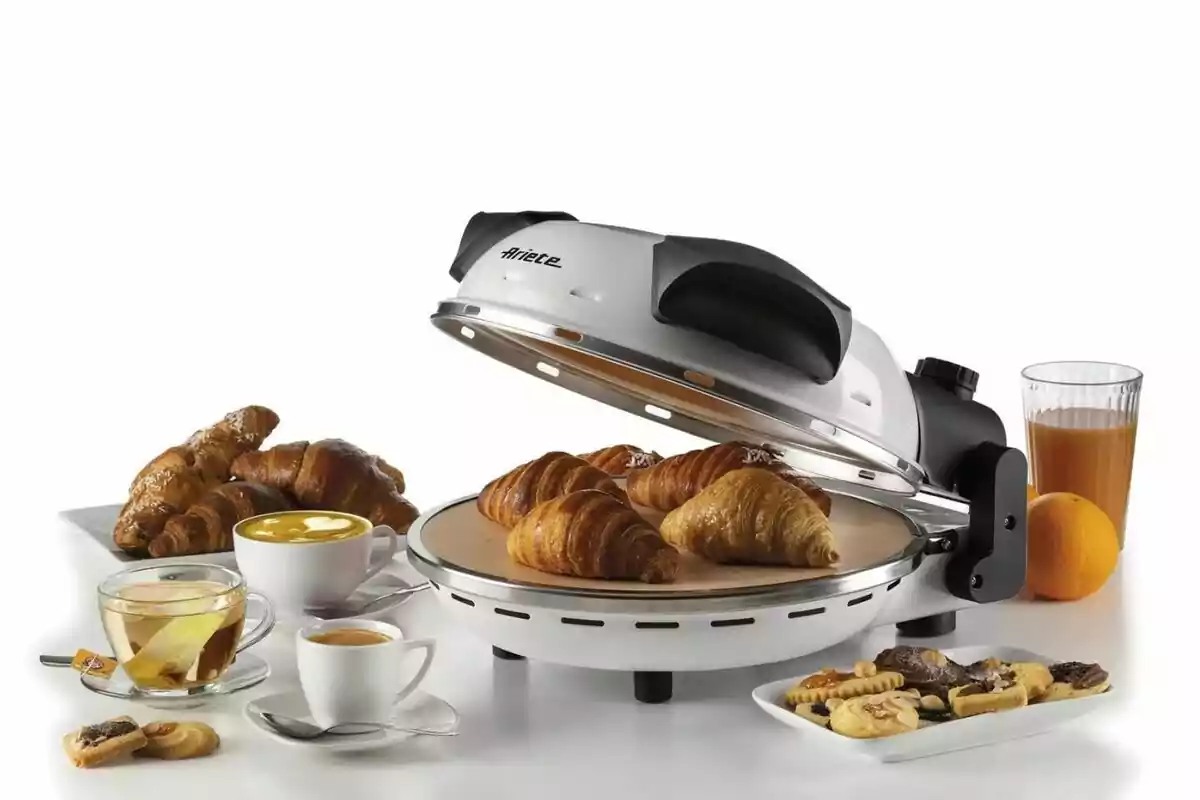 Un forn elèctric de Lidl amb diversos croissants daurats al seu interior, acompanyat de tasses de cafè, te, un got de suc de taronja, una taronja sencera i plats amb galetes i més croissants sobre una taula blanca. Un forn elèctric de Lidl amb diversos croissants daurats al seu interior, acompanyat de tasses de cafè, te, un got de suc de taronja, una taronja sencera i plats amb galetes i més croissants sobre una taula blanca.