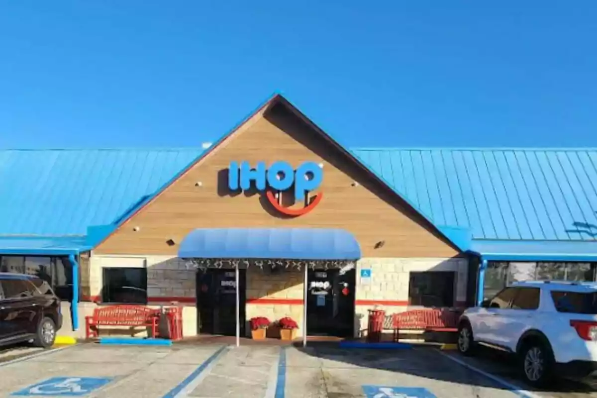 Restaurant building with a blue roof and sign on the facade, surrounded by parked cars. Restaurant building with a blue roof and sign on the facade, surrounded by parked cars.