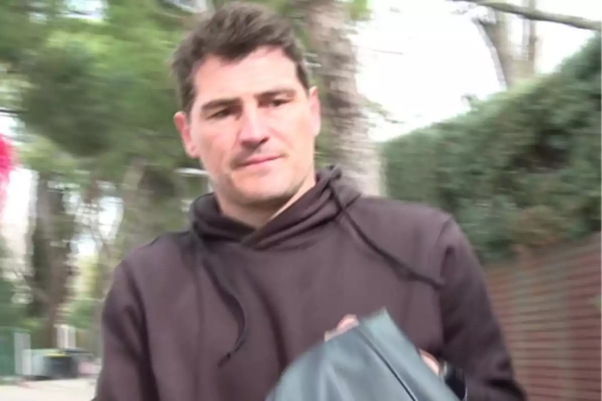 Íker Casillas amb dessuadora marró camina a l'aire lliure amb arbres de fons. Íker Casillas amb dessuadora marró camina a l'aire lliure amb arbres de fons.