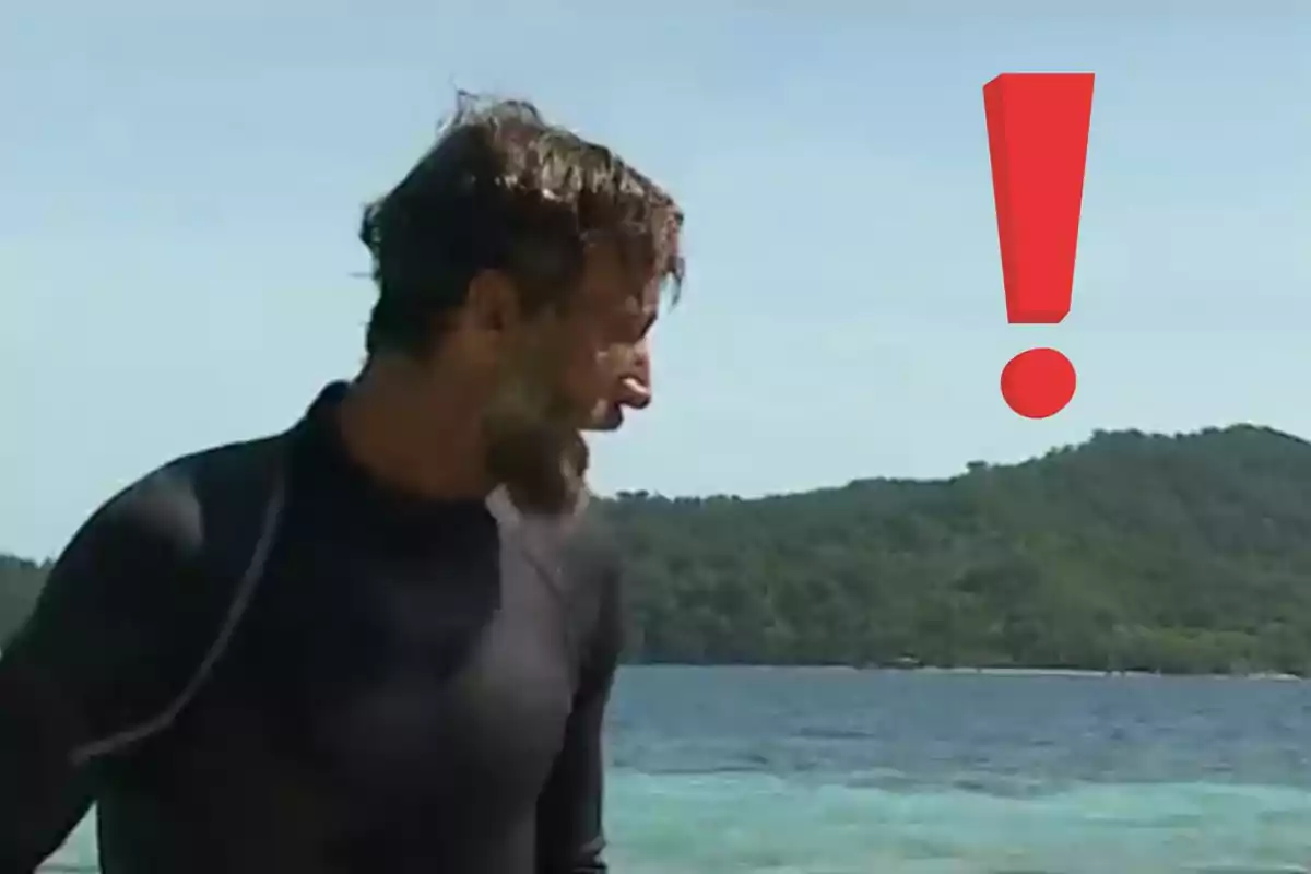 Home amb barba mirant cap a la dreta a la vora del mar amb un gran signe d’exclamació vermell sobre el fons d’una illa