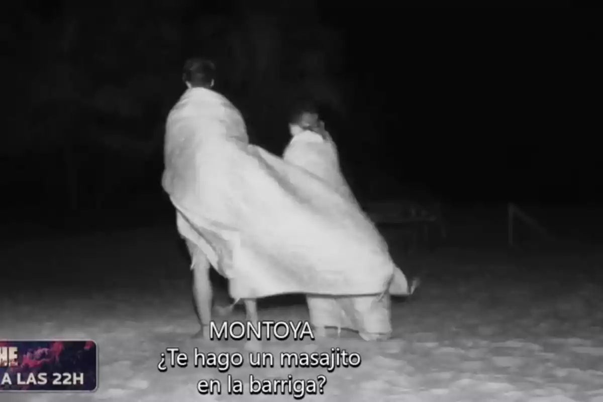 Dues persones caminen per la platja embolicades en una manta durant la nit. Dues persones caminen per la platja embolicades en una manta durant la nit.