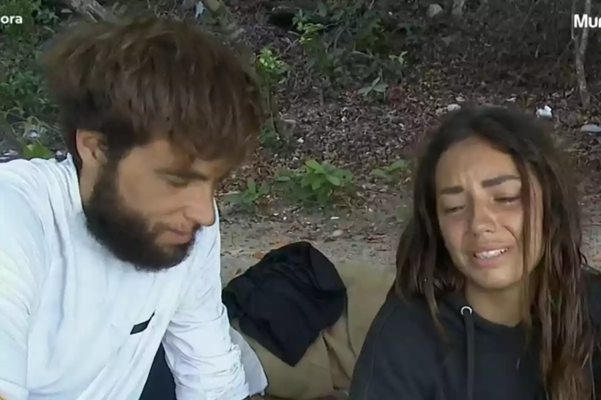 Dues persones amb roba informal assegudes a l’aire lliure en un entorn natural, una d’elles sembla estar trista o plorant Dues persones amb roba informal assegudes a l’aire lliure en un entorn natural, una d’elles sembla estar trista o plorant