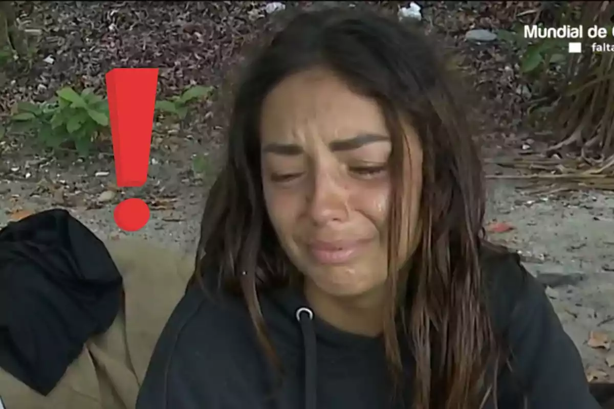 Dona amb expressió de tristesa plorant a l’aire lliure al costat d’un gran signe d’exclamació vermell